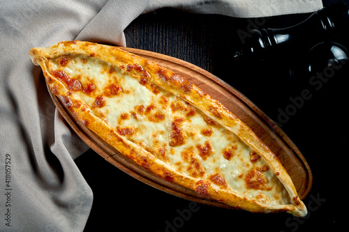Turkish pide dish with tomatoes and salted cheese on black background photo