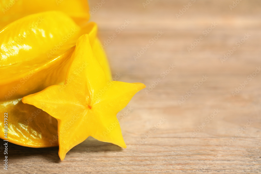 Fototapeta premium Delicious carambola and slice on wooden table, closeup. Space for text