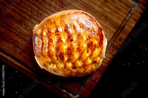 Oven baked turkish bread bun on a wooden tray on a dark background