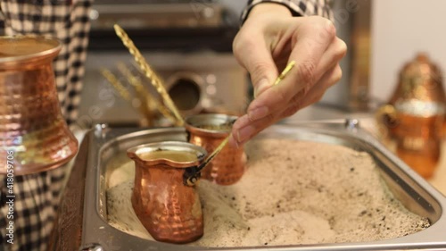 The barista brews natural coffee in copper turks on the sand.