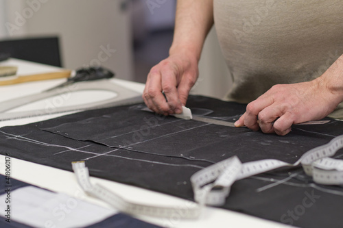 seamstress workplace. Woman seamstress makes pattern with chalk on fabric for sewing clothes in tailor studio. Tailor atelier handmade exclusive clothes making and repair. creative occupation concept © yavdat