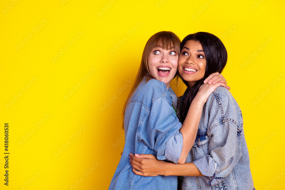 Profile portrait of two impressed charming persons hugging look empty space isolated on yellow color background