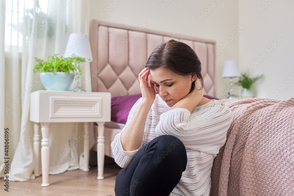 Tired mature woman suffering from headache, migraine, female sitting at home on the floor Tired mature woman suffering from headache, migraine, female sitting at home on the floor