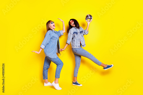 Full body portrait of two carefree excited buddies dark skin hold disco ball isolated on yellow color background