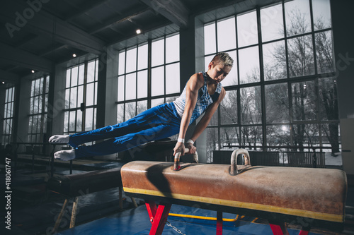 Champion. Little male gymnast training in gym  composed and active. Caucasian fit boy  athlete in sportswear practicing in exercises for strength  balance. Movement  action  motion  dynamic concept