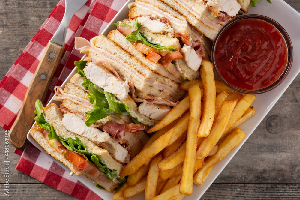 Club sandwich and French fries with ketchup sauce on wooden table Club sandwich and French fries with ketchup sauce on wooden table