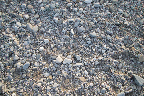 Grey river pebbles and soil texture in a sunny day