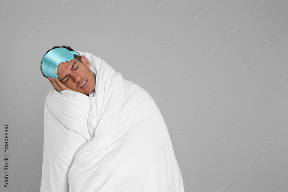 Man wrapped in blanket sleeping on grey background. Space for text Man wrapped in blanket sleeping on grey background. Space for text