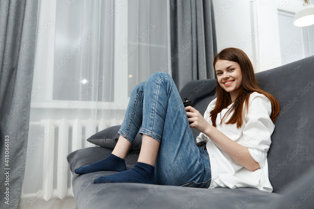 smiling woman sitting on sofa with bent legs in apartment interior smiling woman sitting on sofa with bent legs in apartment interior