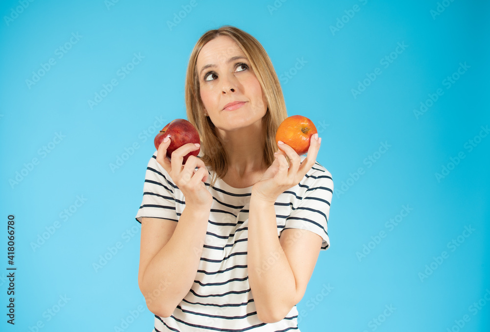 Portrait of a cheerful young woman holding two apples isolated over blue background Portrait of a cheerful young woman holding two apples isolated over blue background