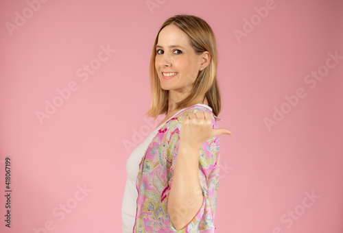 Smiling pretty young woman showing thumb up isolated over pink background