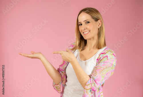 Young woman over isolated pink background pointing fingers to the side © Danko