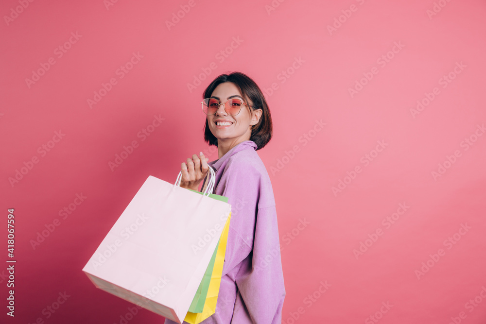 Woman wearing casual sweater on background happy enjoying shopping holding colorful bags wearing summer sunglasses Woman wearing casual sweater on background happy enjoying shopping holding colorful bags wearing summer sunglasses