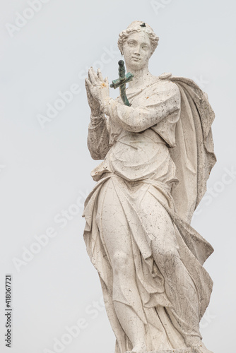 Ancient statue of beautiful praying Saint Angel with sword in her chest at the top of Arsenal in Venice, Italy, details, closeup.