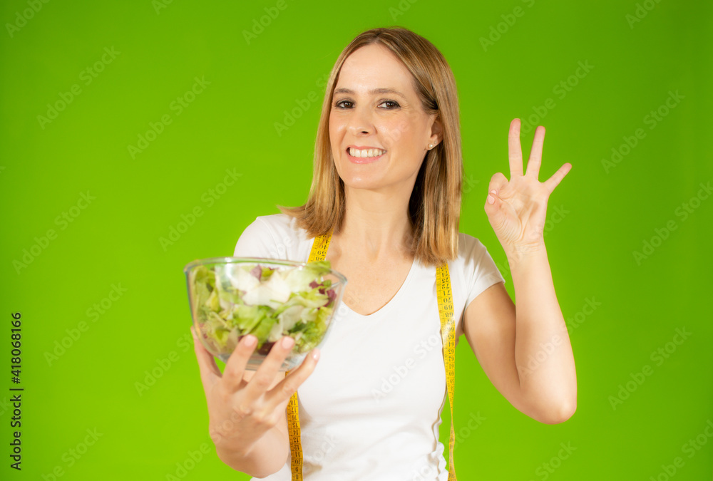 Woman diet concept portrait. Young woman hold green salad and measure tape. Isolated portrait. Woman diet concept portrait. Young woman hold green salad and measure tape. Isolated portrait.