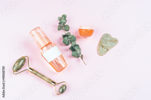 Fototapeta Naklejka Na Ścianę i Meble -  Bottles with care cosmetics, massager and scraper on pink background