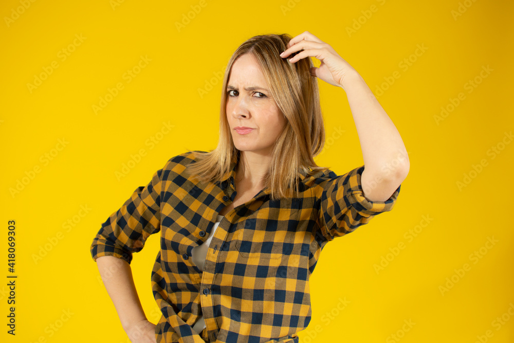 Attractive thoughtful young woman standing isolated over yellow background Attractive thoughtful young woman standing isolated over yellow background