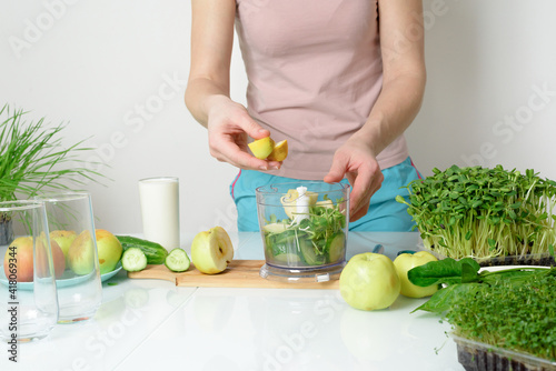 step-by-step recipe for making smoothies from micro-green apples cucumber and spinach. woman hands cut vegetables and put them in blender for whipping eco organic fresh food detox on light background