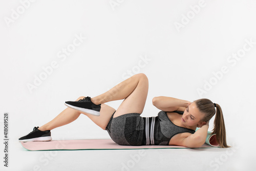 fitness woman in sportswear making abs exercises in studio on white background