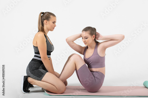 fitness women in sportswear making abs exercises in studio on white background