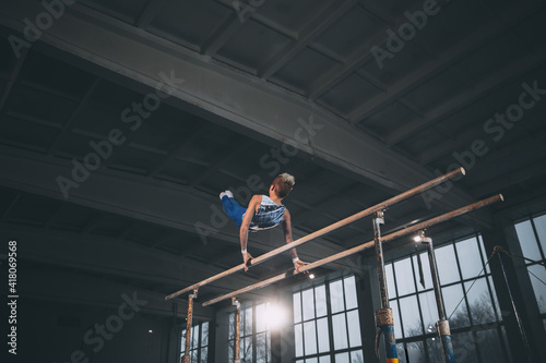 Skillful. Little male gymnast training in gym, composed and active. Caucasian fit boy, athlete in sportswear practicing in exercises for strength, balance. Movement, action, motion, dynamic concept © master1305