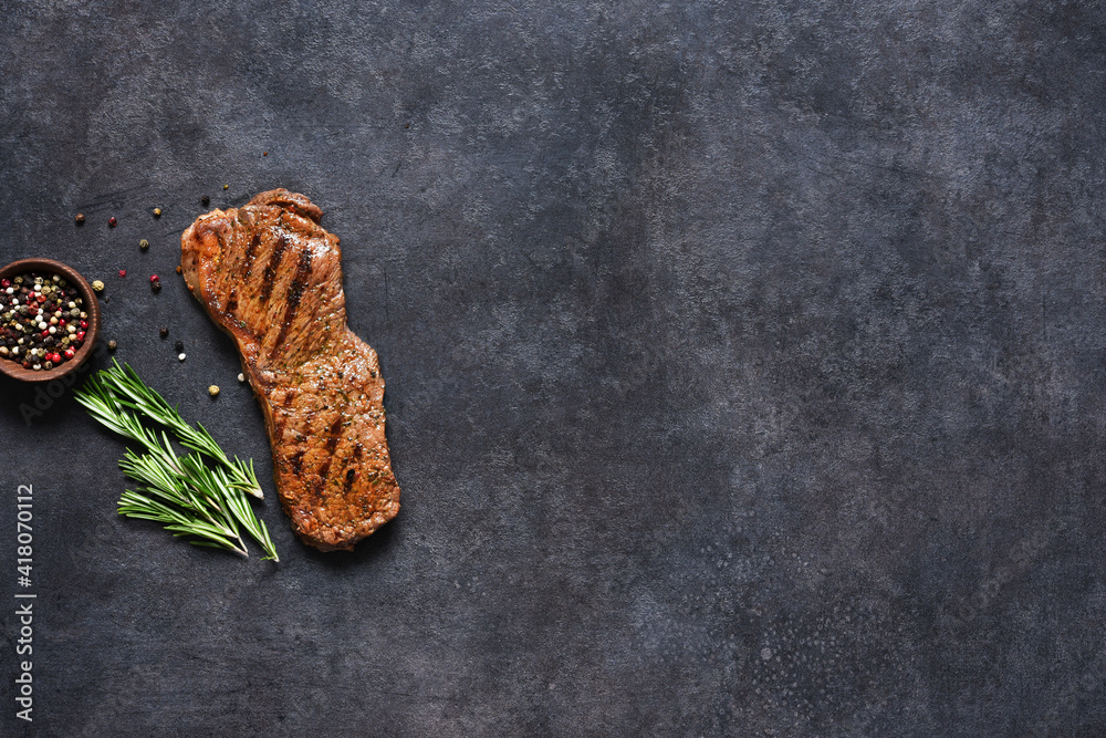 Fried beef steak with rosemary and spices on a black concrete background, top view. Fried beef steak with rosemary and spices on a black concrete background, top view.