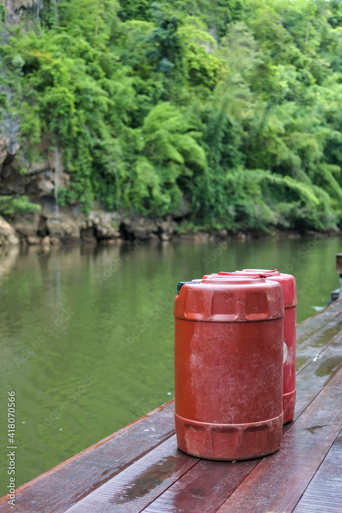 Red barrels of oil on wet wooden floor with beautiful river, forest and cliff. Red barrels of oil on wet wooden floor with beautiful river, forest and cliff.