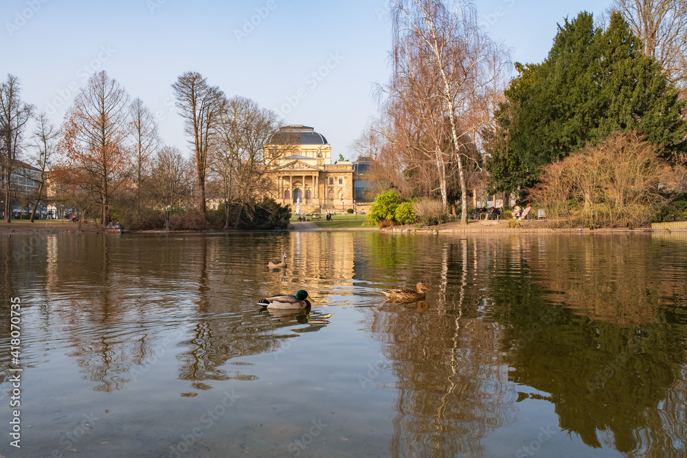 View over a pond with ducks in the park of Wiesbaden / Germany towards the opera house 