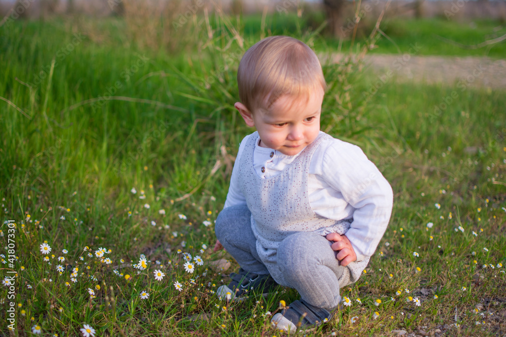 Baby Playing In A Field Of Spring Flowers. Spring Concept Baby Playing In A Field Of Spring Flowers. Spring Concept