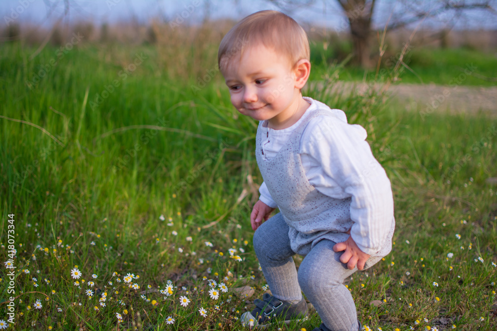 Baby Playing In A Field Of Spring Flowers. Spring Concept Baby Playing In A Field Of Spring Flowers. Spring Concept
