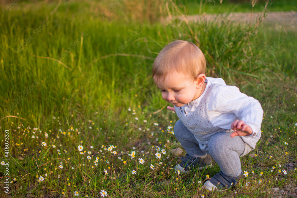 Baby Playing In A Field Of Spring Flowers. Spring Concept Baby Playing In A Field Of Spring Flowers. Spring Concept