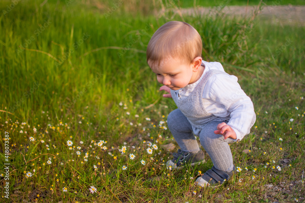 Baby Playing In A Field Of Spring Flowers. Spring Concept Baby Playing In A Field Of Spring Flowers. Spring Concept