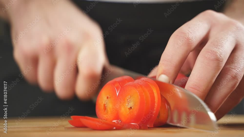 Slicing sweet peppers on a chopping board by a chef, close-up of men's hands cutting red peppers with a knife, slow motion. healthy food concept. Slicing sweet peppers on a chopping board by a chef, close-up of men's hands cutting red peppers with a knife, slow motion. healthy food concept.