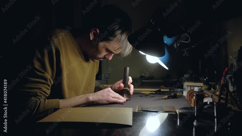 European male tanner left handed working on workplace with leather. Hand made concept. European male tanner left handed working on workplace with leather. Hand made concept.