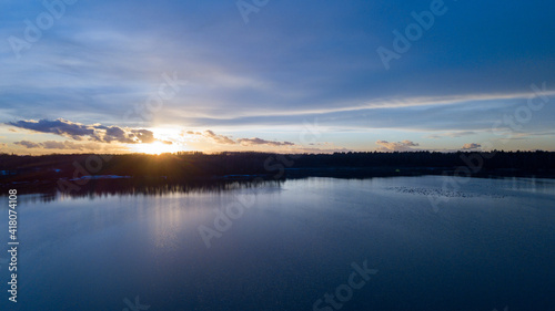 Aerial view of a beautiful and dramatic sunset over a forest lake reflected in the water, landscape drone shot. Blakheide, Beerse, Belgium. High quality photo