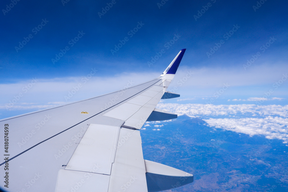 Obraz premium Photo of airplane wing with clouds background, horizon line and clear blue sky