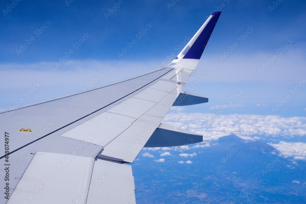 Obraz premium Photo of airplane wing with clouds background, horizon line and clear blue sky