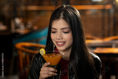 Portrait of a beautiful young Indian girl drinking juice while sitting in a restaurant.