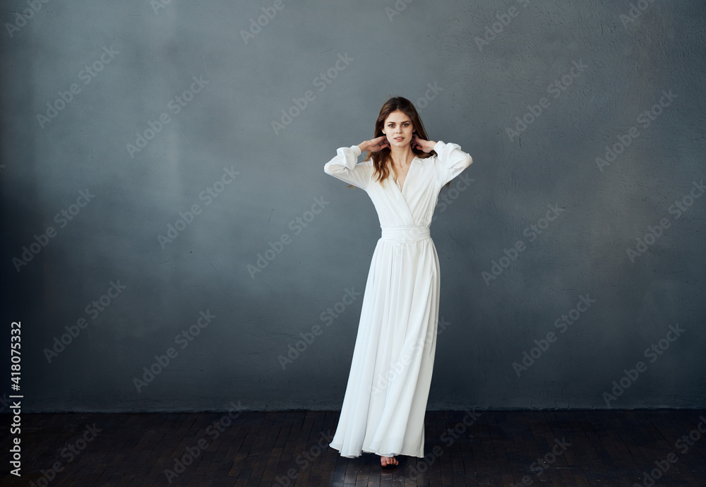Charming lady in a white dress on a gray background dance gesticulating with her hands model Charming lady in a white dress on a gray background dance gesticulating with her hands model