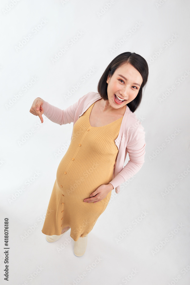 happy young pregnant woman on white background, woman points finger to belly happy young pregnant woman on white background, woman points finger to belly