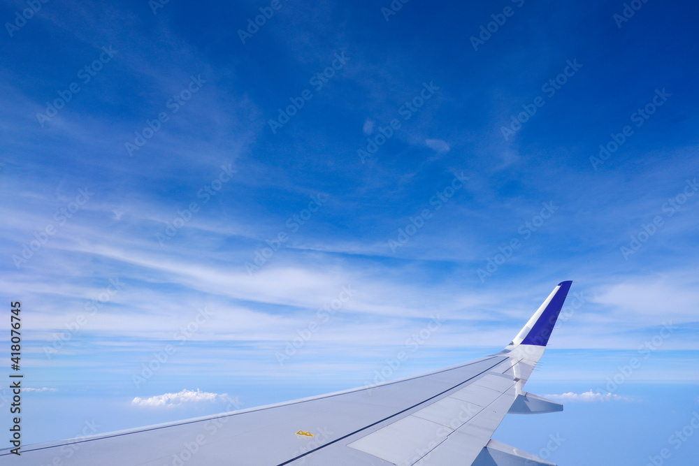 Fototapeta premium Photo of airplane wing with clouds background, horizon line and clear blue sky
