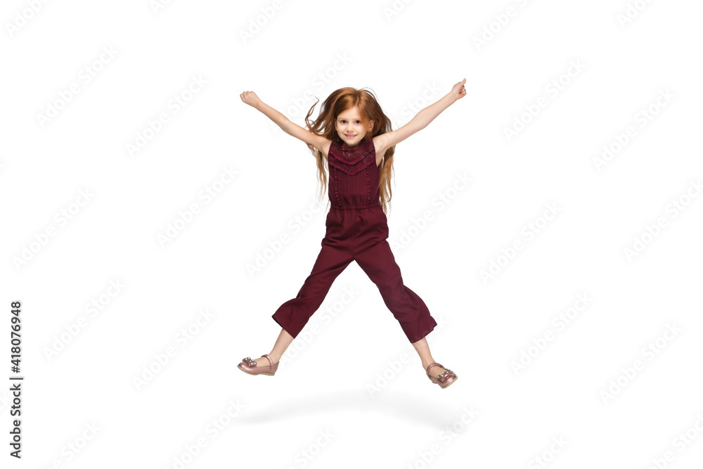Jumping, running. Happy, smiley little caucasian girl isolated on white studio background with copyspace for ad. Looks happy, cheerful. Childhood, education, human emotions, facial expression concept.