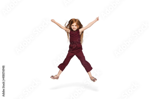 Jumping, running. Happy, smiley little caucasian girl isolated on white studio background with copyspace for ad. Looks happy, cheerful. Childhood, education, human emotions, facial expression concept.