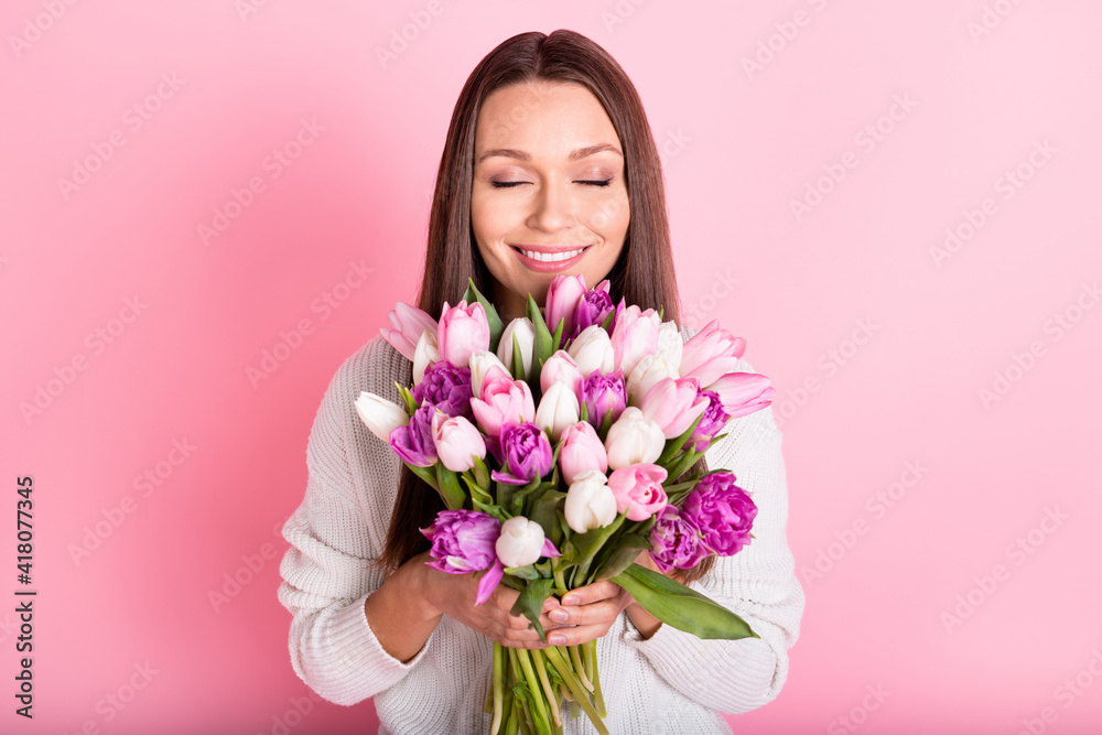 Photo of joyful happy young attractive sweet lady smell flowers isolated on pastel pink color background Photo of joyful happy young attractive sweet lady smell flowers isolated on pastel pink color background