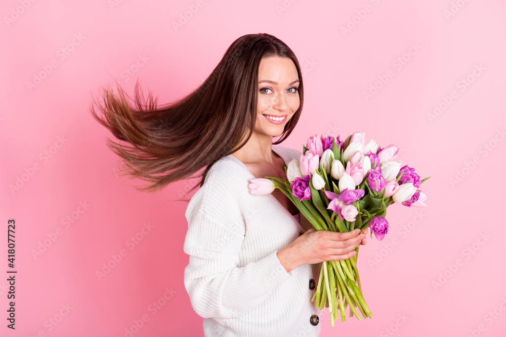 Profile side photo of joyful happy young woman smile hold tulips isolated on pastel pink color background Profile side photo of joyful happy young woman smile hold tulips isolated on pastel pink color background