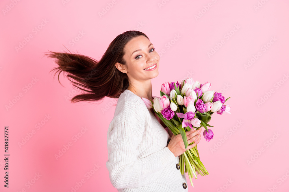 Profile side photo of charming sweet cute young woman hold flowers fly hair isolated on pastel pink color background Profile side photo of charming sweet cute young woman hold flowers fly hair isolated on pastel pink color background