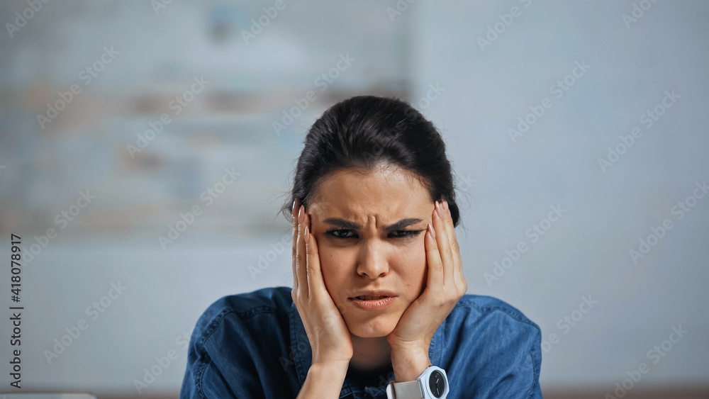 upset woman looking at camera while suffering from headache