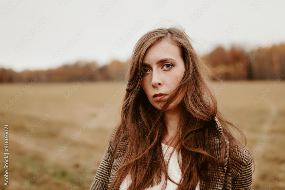 Sad girl with blue eyes. Portrait of a girl in brown tones. Walk through the woods. Autumn colors. Girl with long hair