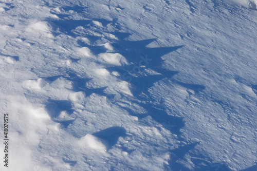 Snowy ground with blue shadows. Close-up. Arctic winter background