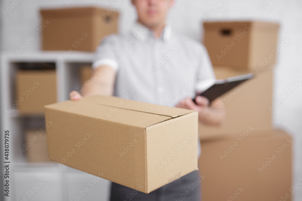 postman with box and clipboard in warehouse or storage